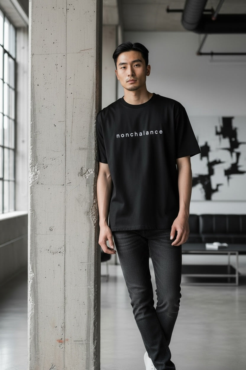 Man wearing a black t-shirt with 'nonchalance' text in an urban setting